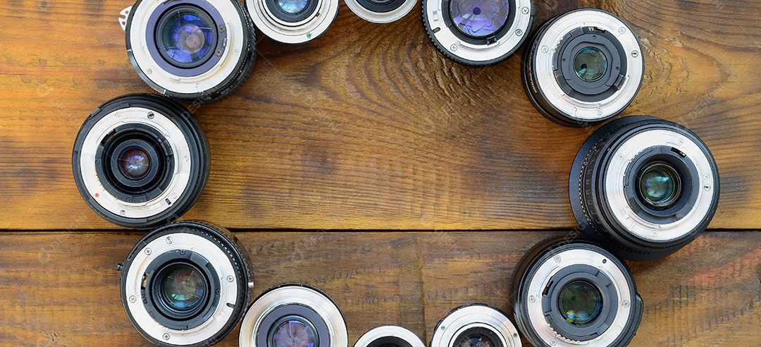 Várias lentes fotográficas repousam sobre um fundo de madeira marrom