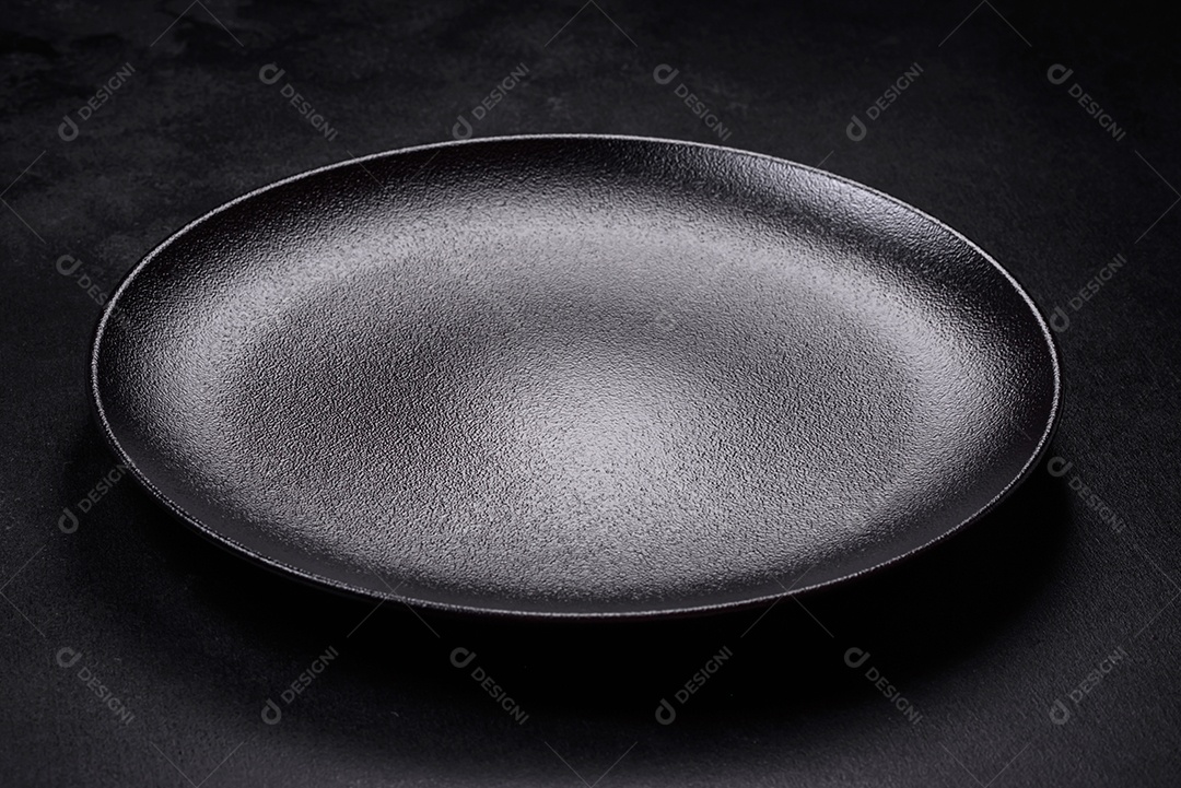 Placa cerâmica preta vazia sobre um fundo escuro de concreto. Preparando a mesa para um jantar em família