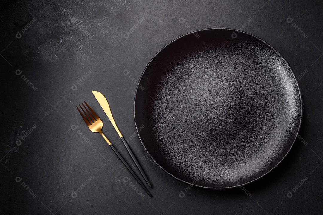 Placa cerâmica preta vazia sobre um fundo escuro de concreto. Preparando a mesa para um jantar em família