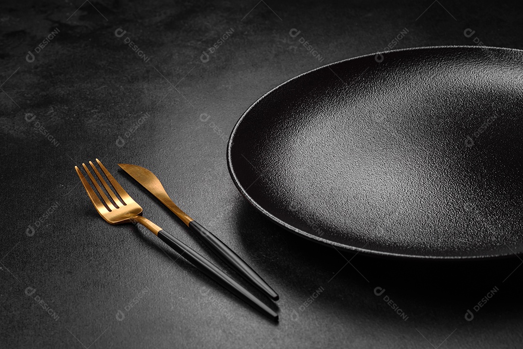 Placa cerâmica preta vazia sobre um fundo escuro de concreto. Preparando a mesa para um jantar em família
