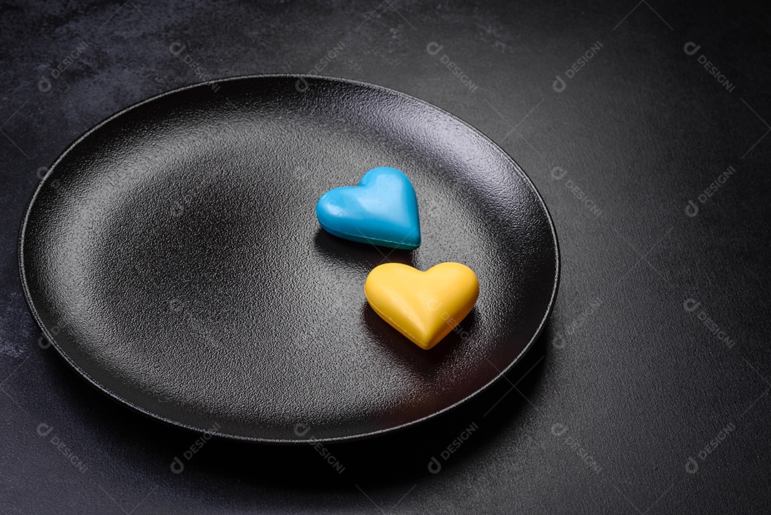 Corações de chocolate nas cores da bandeira ucraniana num prato de cerâmica preto. Dia dos Namorados em cores ucranianas