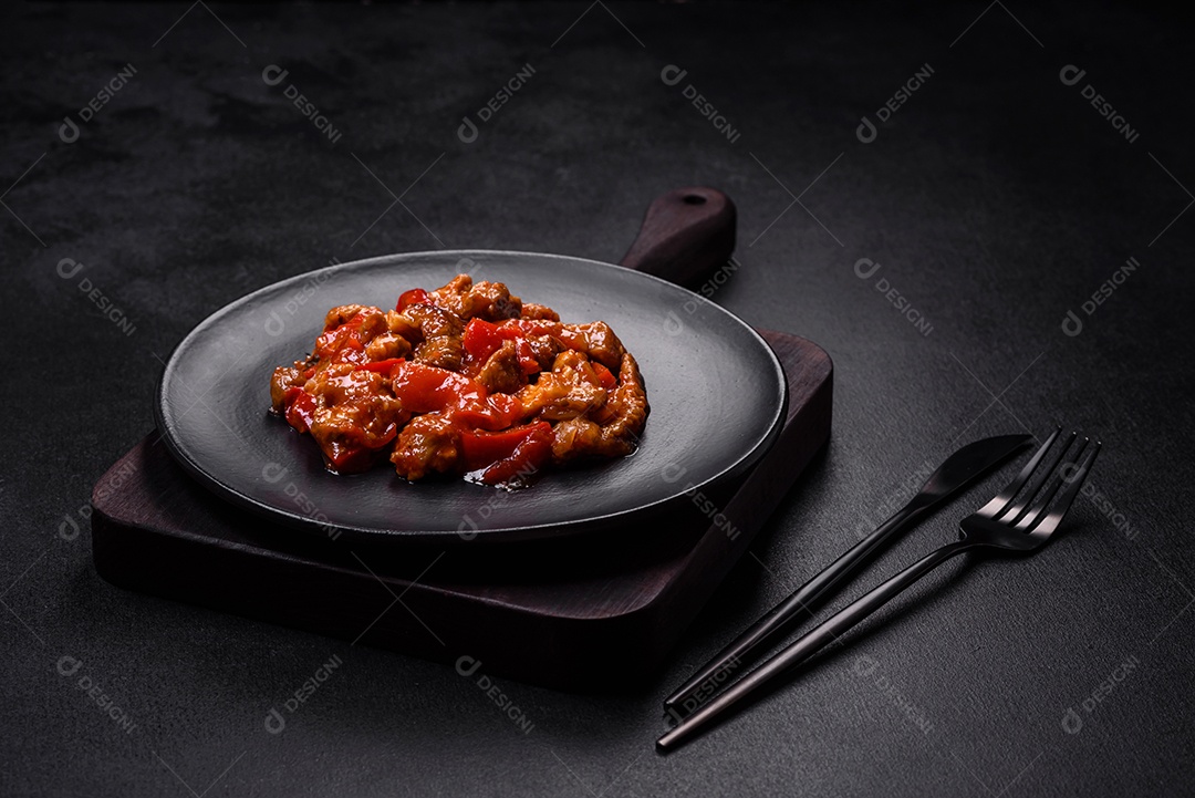 Deliciosa carne suculenta com pimenta e molho em uma placa de cerâmica preta sobre um fundo escuro de concreto