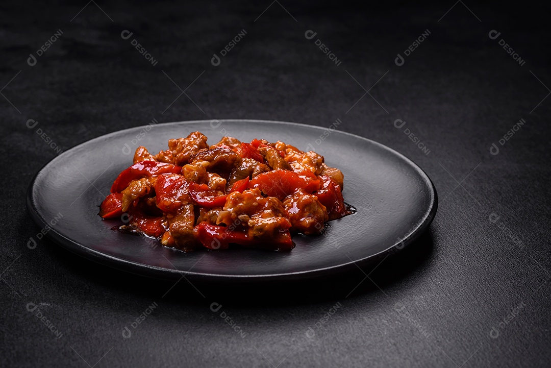 Deliciosa carne suculenta com pimenta e molho em uma placa de cerâmica preta sobre um fundo escuro de concreto