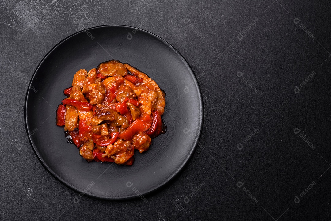 Deliciosa carne suculenta com pimenta e molho em uma placa de cerâmica preta sobre um fundo escuro de concreto