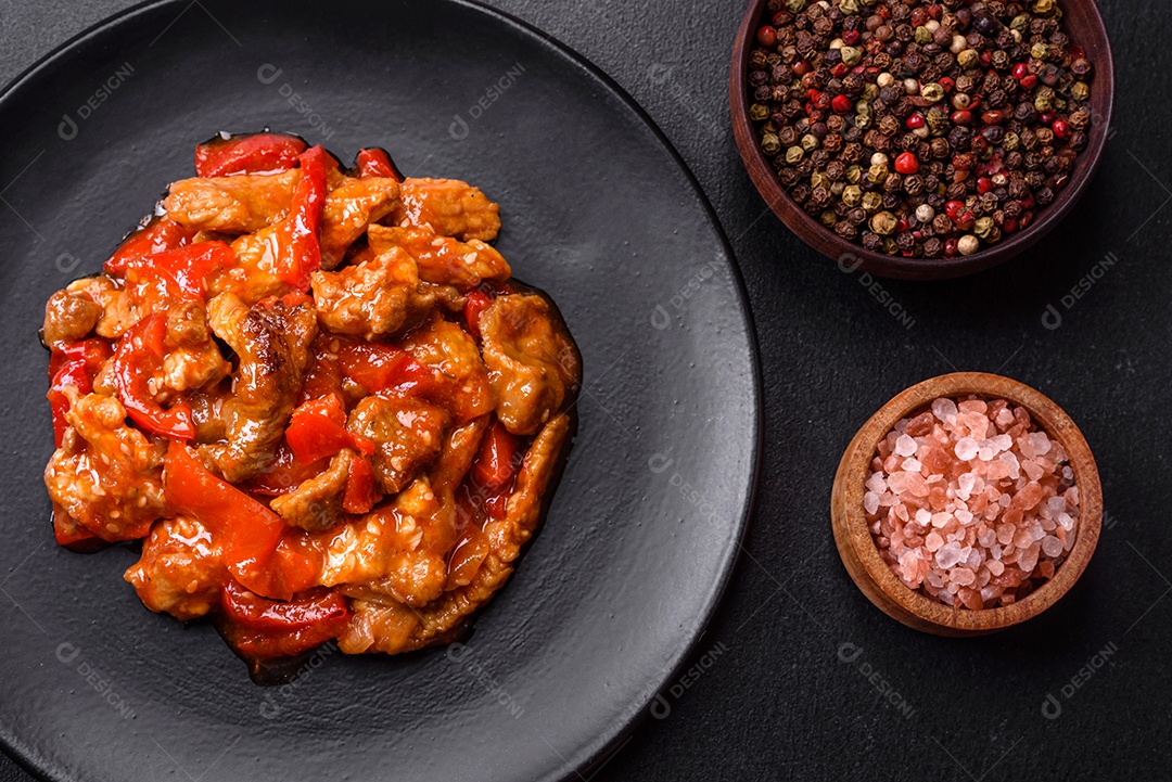 Deliciosa carne suculenta com pimenta e molho em uma placa de cerâmica preta sobre um fundo escuro de concreto