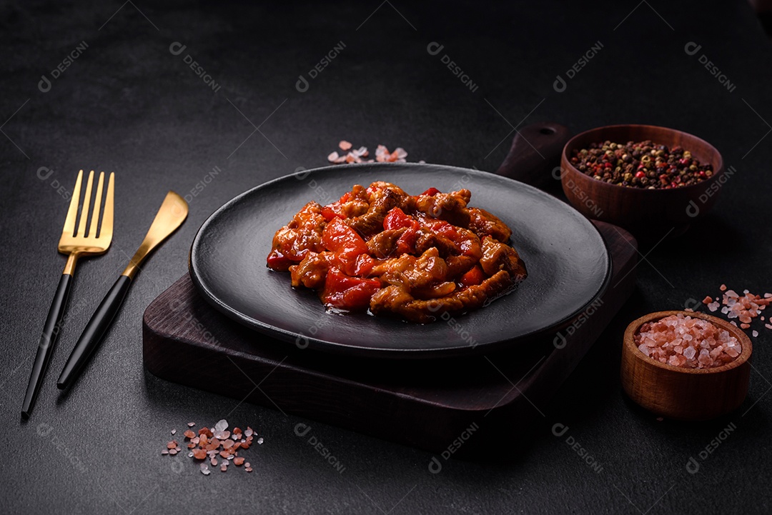 Deliciosa carne suculenta com pimenta e molho em uma placa de cerâmica preta sobre um fundo escuro de concreto