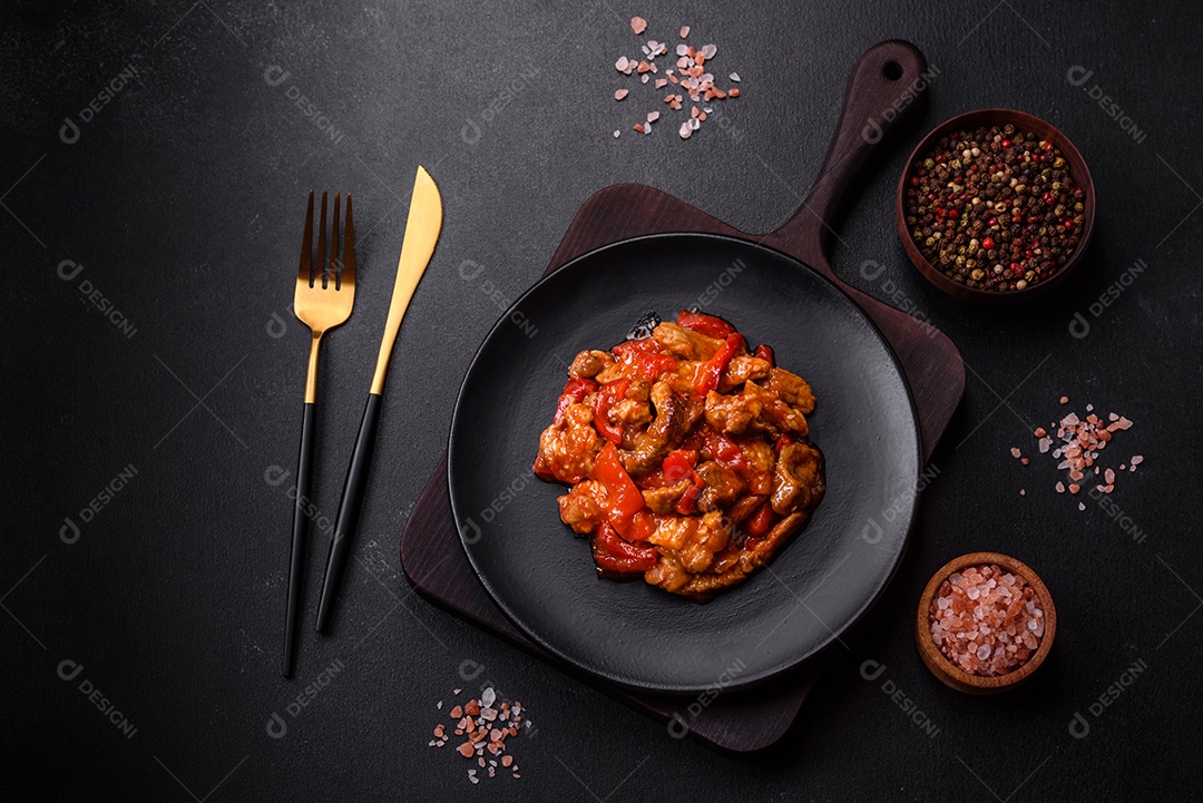 Deliciosa carne suculenta com pimenta e molho em uma placa de cerâmica preta sobre um fundo escuro de concreto