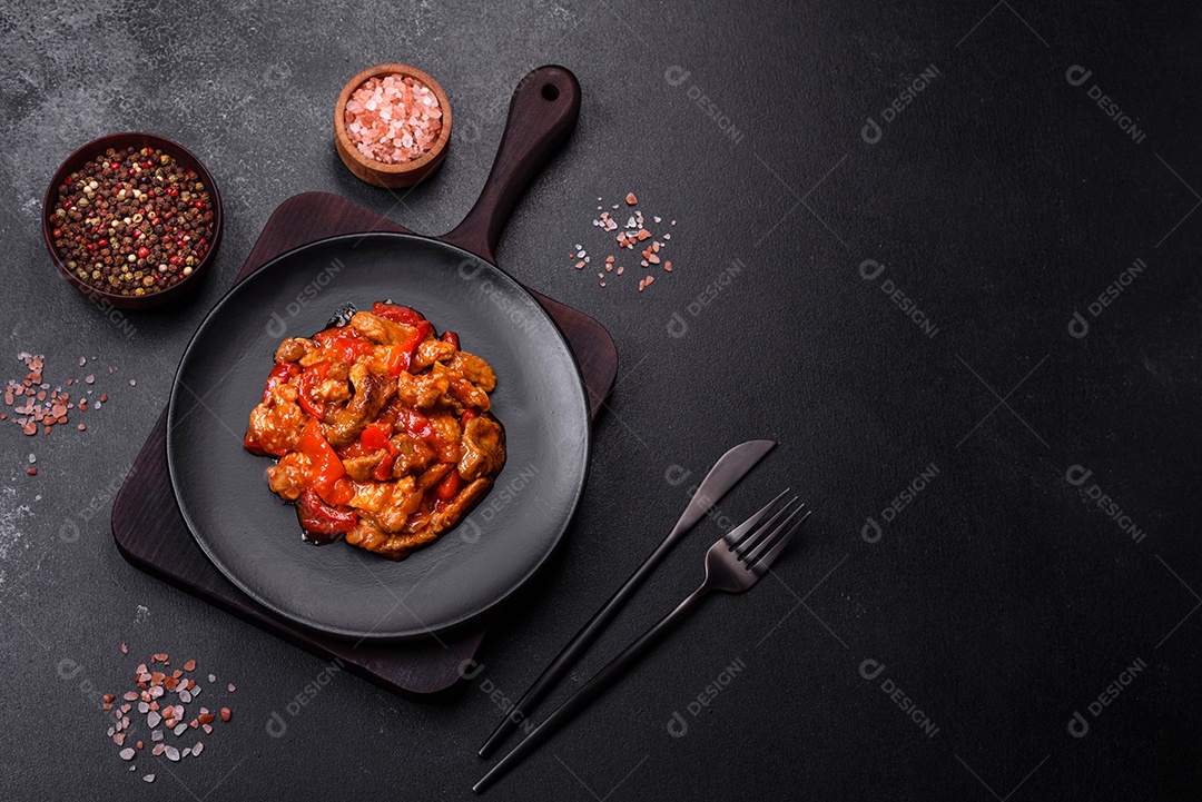Deliciosa carne suculenta com pimenta e molho em uma placa de cerâmica preta sobre um fundo escuro de concreto