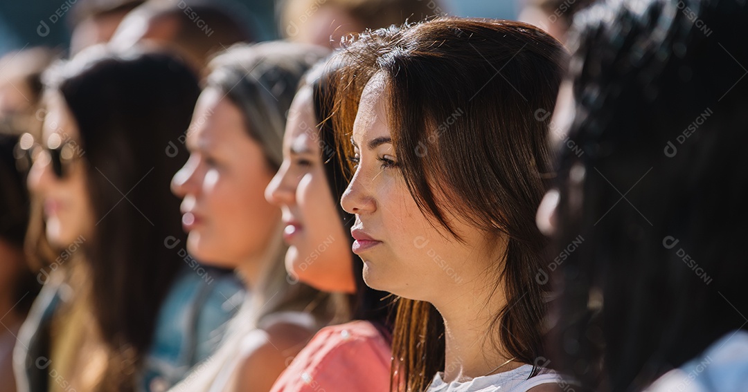 Grupo de mulheres ao ar livre, olhando para frente com uma expressão séria. Manifestantes, direitos das mulheres.