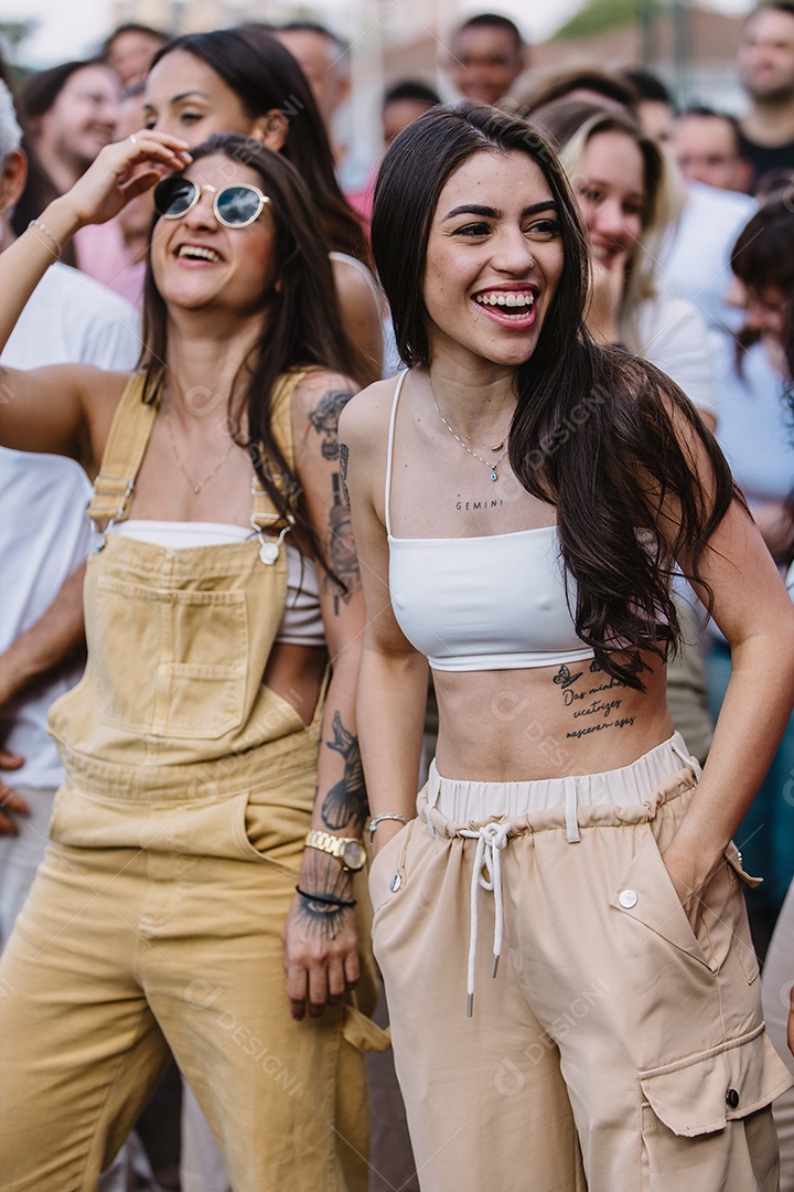 Mulheres sorridentes conversando no meio da multidão.