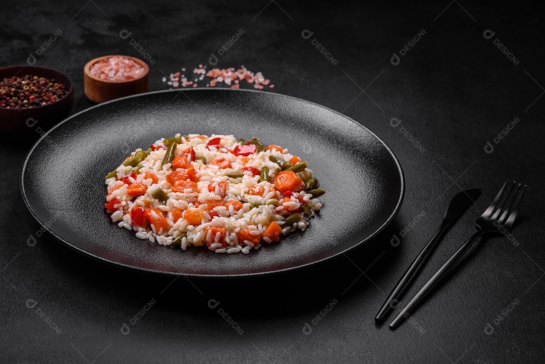 Delicioso risoto fresco com legumes, especiarias e ervas em uma placa preta sobre um fundo escuro de concreto