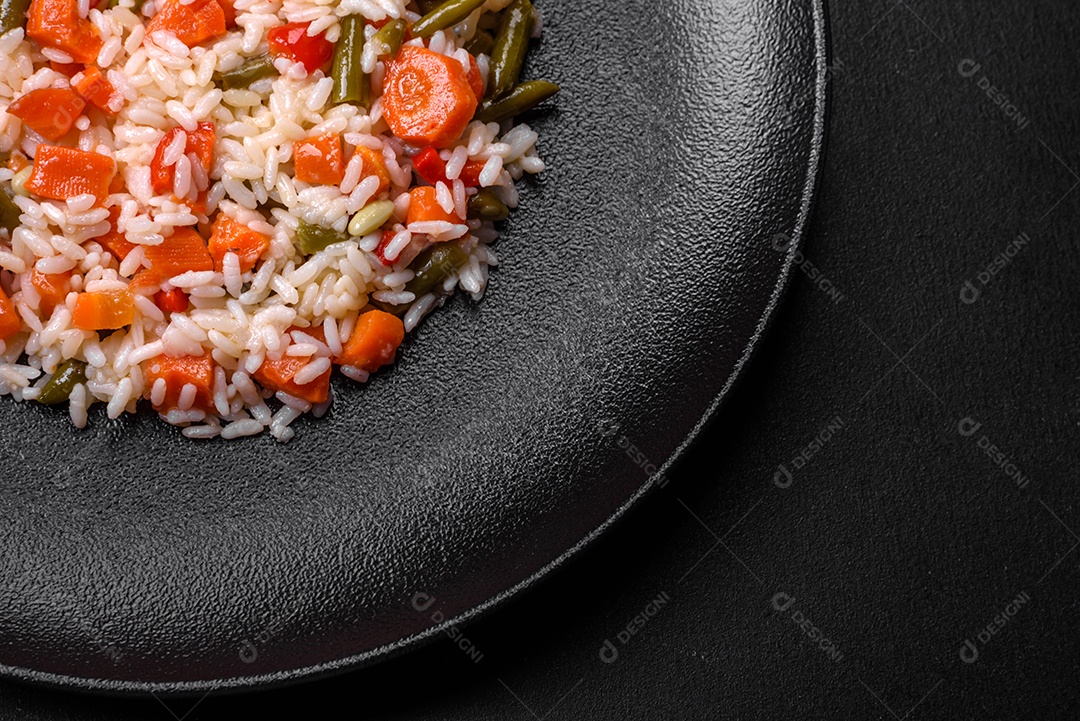 Delicioso risoto fresco com legumes, especiarias e ervas em uma placa preta sobre um fundo escuro de concreto