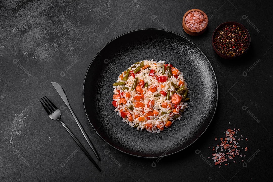 Delicioso risoto fresco com legumes, especiarias e ervas em uma placa preta sobre um fundo escuro de concreto