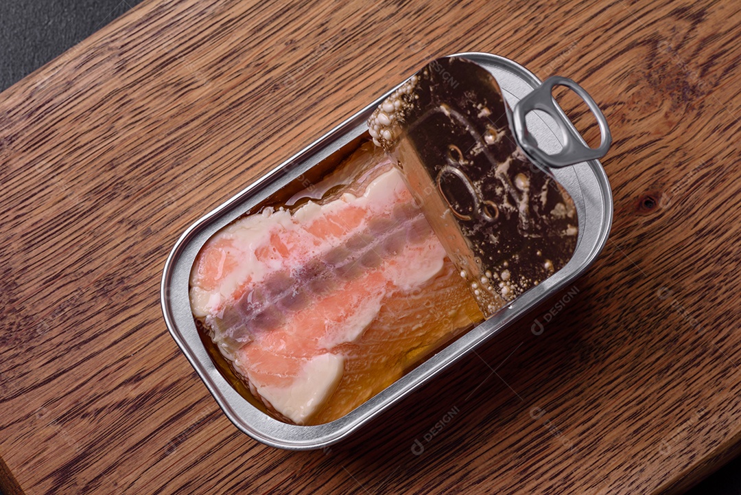 Lata retangular de estanho ou alumínio de salmão enlatado com chave sobre fundo escuro de concreto