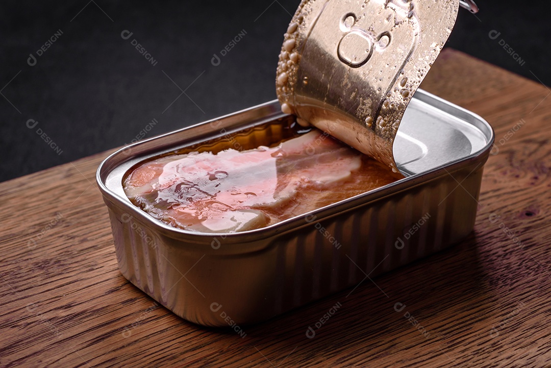 Lata retangular de estanho ou alumínio de salmão enlatado com chave sobre fundo escuro de concreto