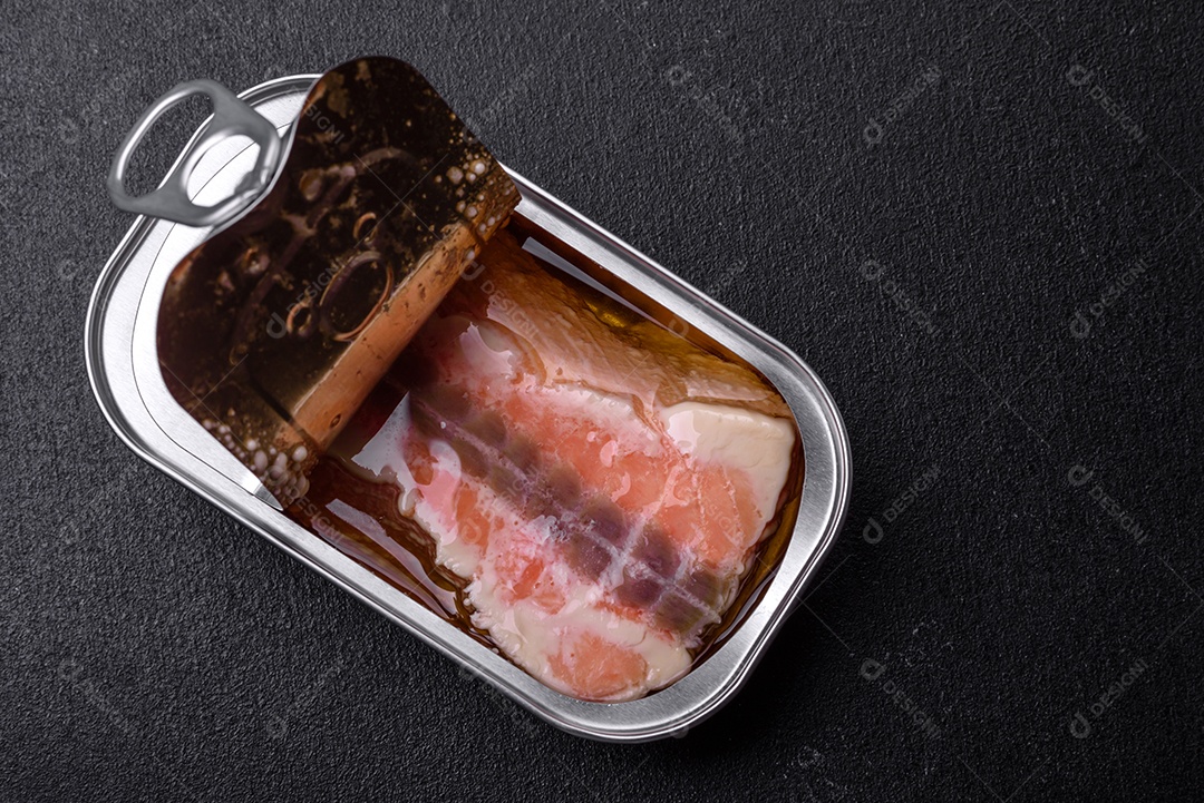 Lata retangular de estanho ou alumínio de salmão enlatado com chave sobre fundo escuro de concreto