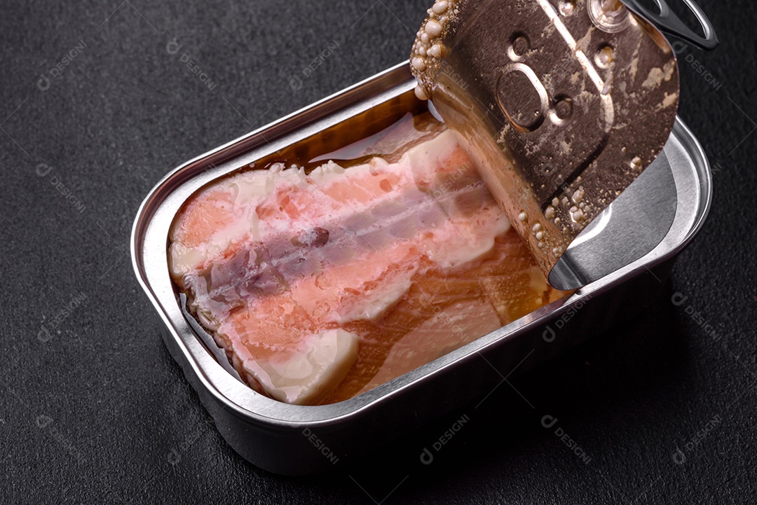 Lata retangular de estanho ou alumínio de salmão enlatado com chave sobre fundo escuro de concreto