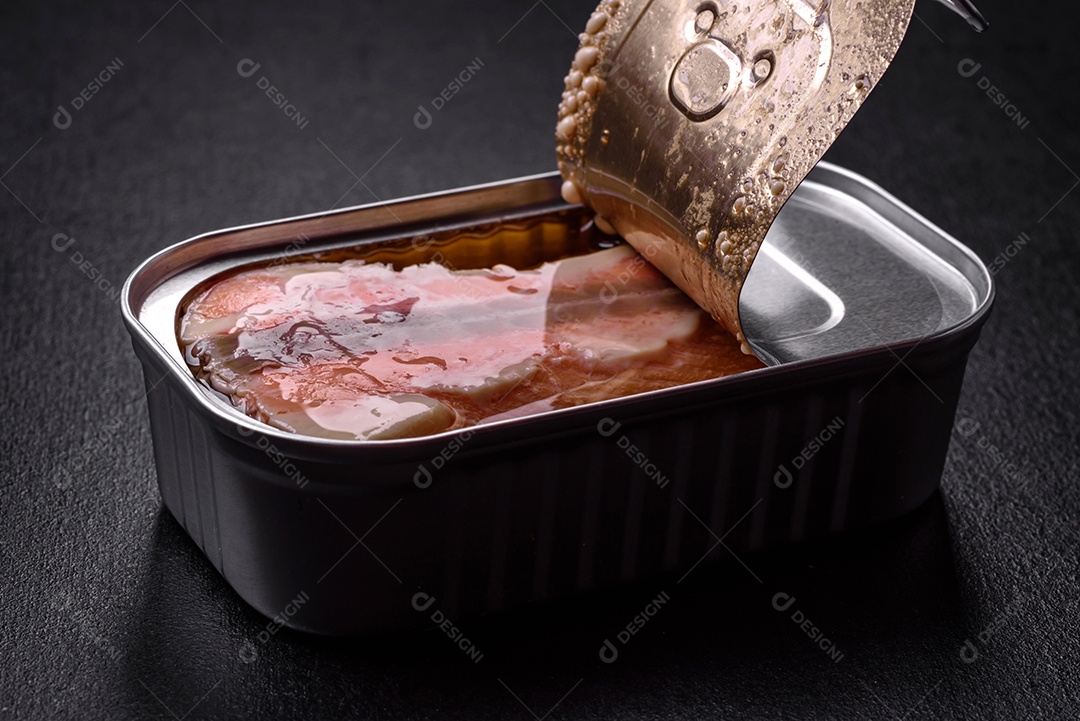 Lata retangular de estanho ou alumínio de salmão enlatado com chave sobre fundo escuro de concreto