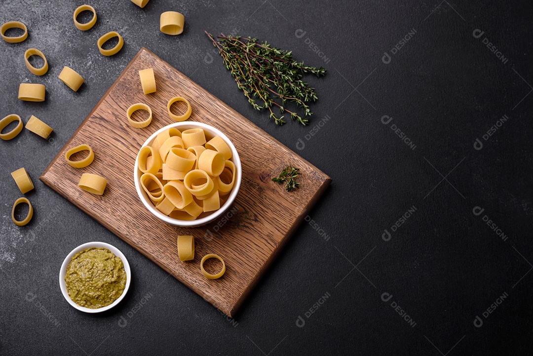 Massa crua e crua numa tigela de cerâmica branca com especiarias e ervas sobre um fundo escuro de concreto