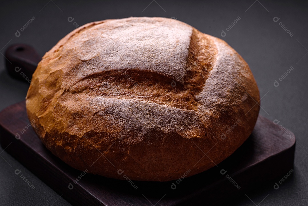 Lindo e delicioso pão branco redondo recém-assado sobre um fundo escuro de concreto