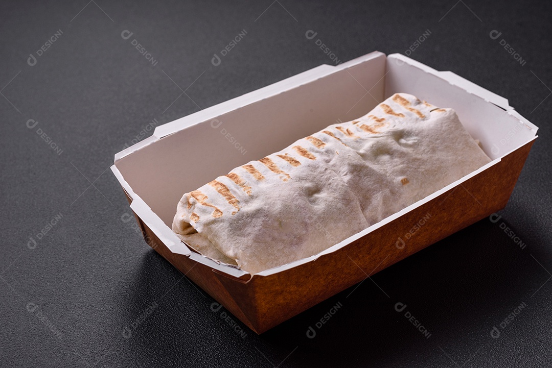 Delicioso shawarma fresco com tomate, pimentão, pepino e molhos em um fundo escuro de concreto. Comida rápida