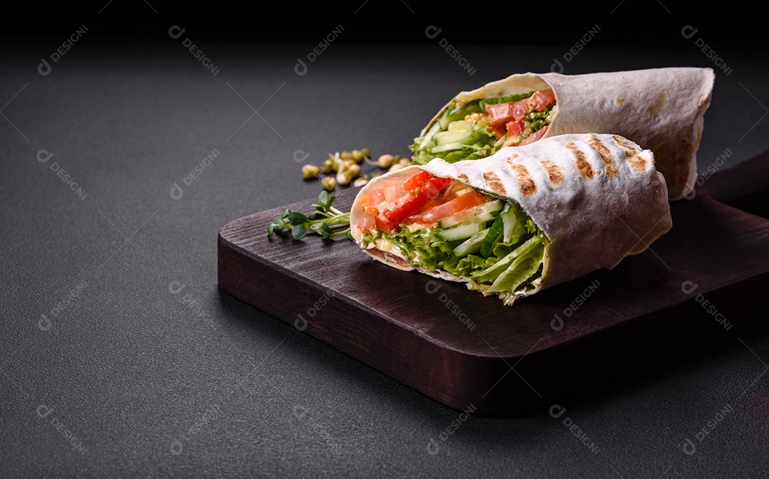 Delicioso shawarma fresco com tomate, pimentão, pepino e molhos em um fundo escuro de concreto. Comida rápida