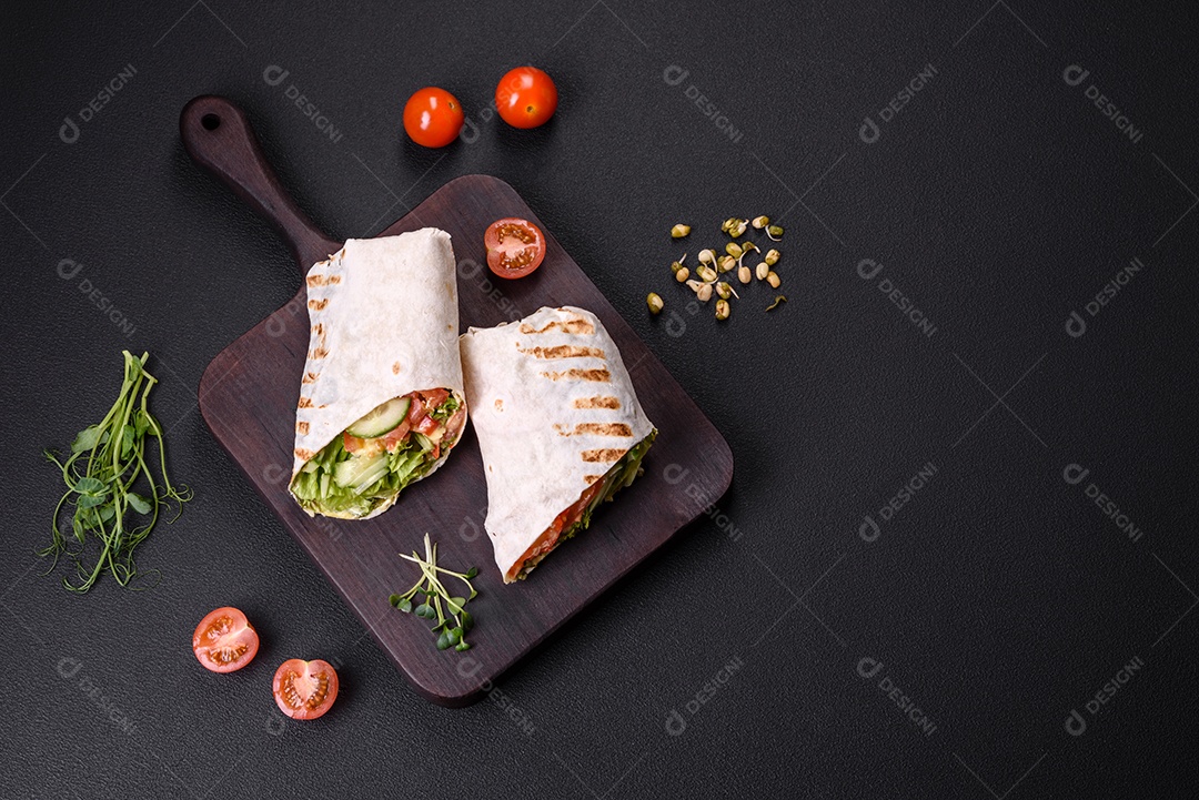 Delicioso shawarma fresco com tomate, pimentão, pepino e molhos em um fundo escuro de concreto. Comida rápida