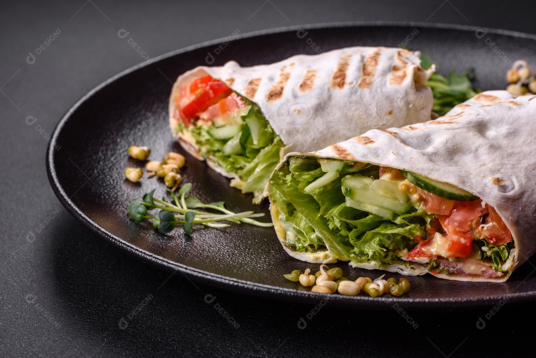 Delicioso shawarma fresco com tomate, pimentão, pepino e molhos em um fundo escuro de concreto. Comida rápida