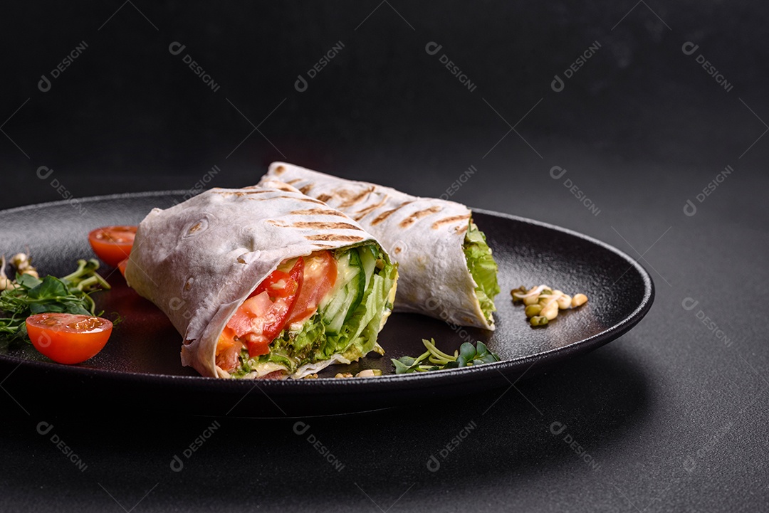 Delicioso shawarma fresco com tomate, pimentão, pepino e molhos em um fundo escuro de concreto. Comida rápida