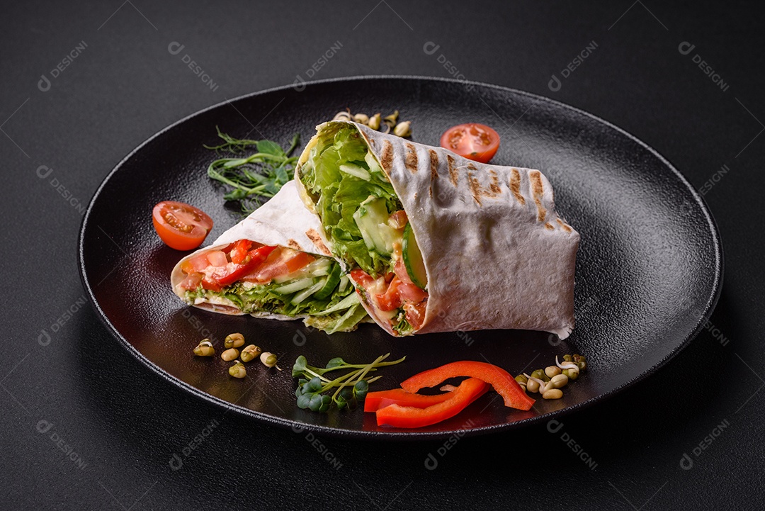 Delicioso shawarma fresco com tomate, pimentão, pepino e molhos em um fundo escuro de concreto. Comida rápida