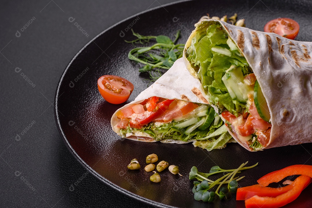 Delicioso shawarma fresco com tomate, pimentão, pepino e molhos em um fundo escuro de concreto. Comida rápida