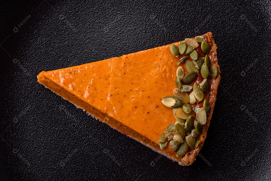 Linda torta de abóbora saborosa com fatias em uma placa de cerâmica preta sobre um fundo escuro de concreto