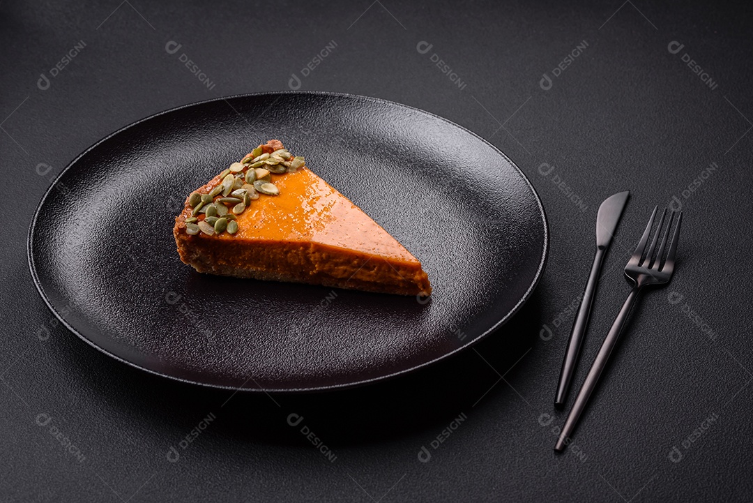 Linda torta de abóbora saborosa com fatias em uma placa de cerâmica preta sobre um fundo escuro de concreto