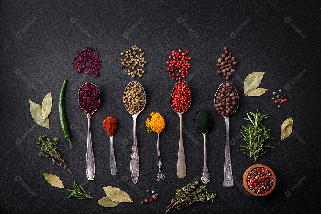 Vários tipos de especiarias em colheres de metal páprica, tomate, curry