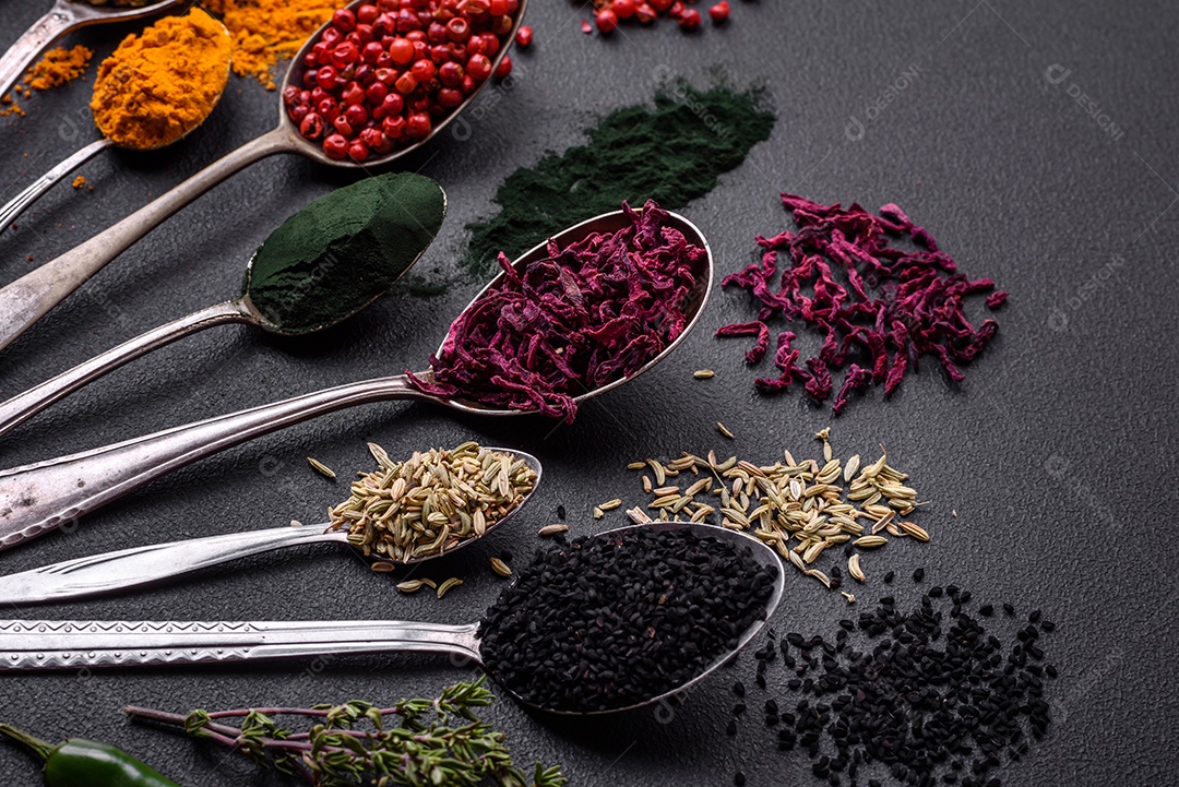 Vários tipos de especiarias em colheres de metal páprica, tomate, curry, beterraba, cominho, açafrão