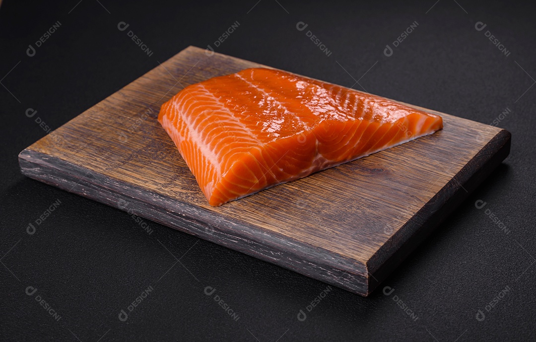 Filé de peixe salmão vermelho cru com sal, especiarias e ervas sobre um fundo escuro de concreto