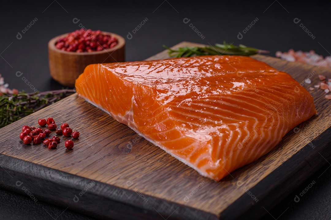 Filé de peixe salmão vermelho cru com sal, especiarias e ervas sobre um fundo escuro de concreto