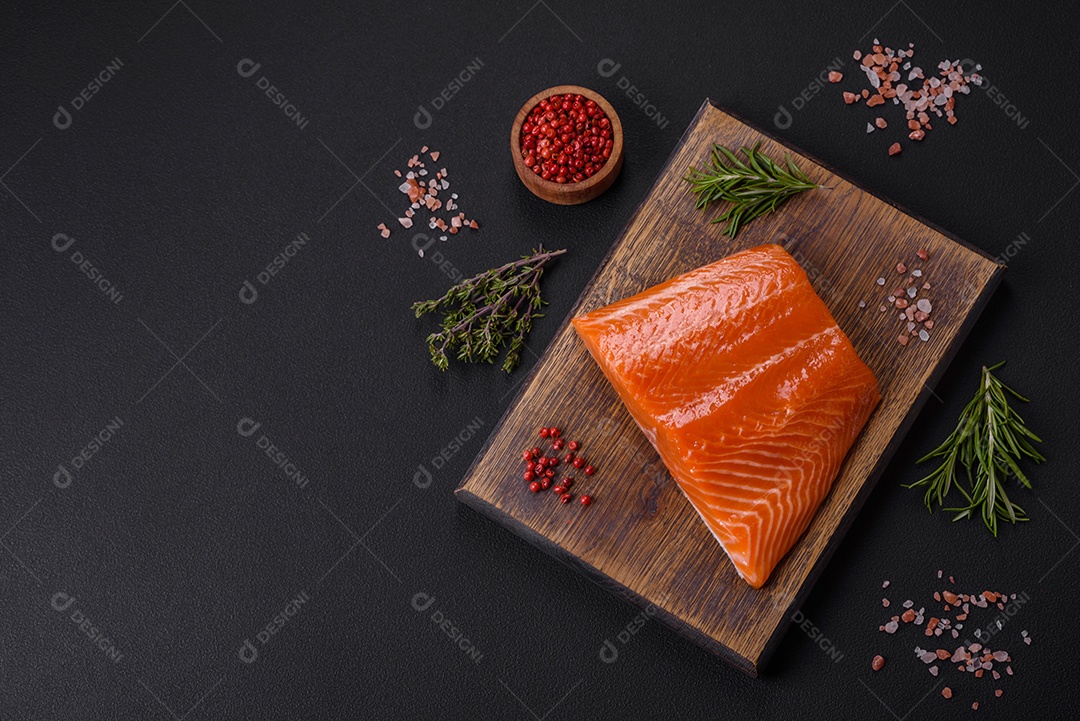 Filé de peixe salmão vermelho cru com sal, especiarias e ervas sobre um fundo escuro de concreto