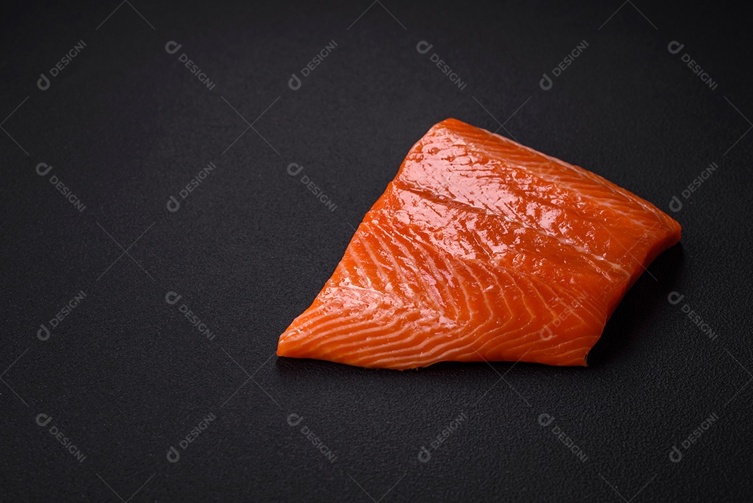 Filé de peixe salmão vermelho cru com sal, especiarias e ervas sobre um fundo escuro de concreto