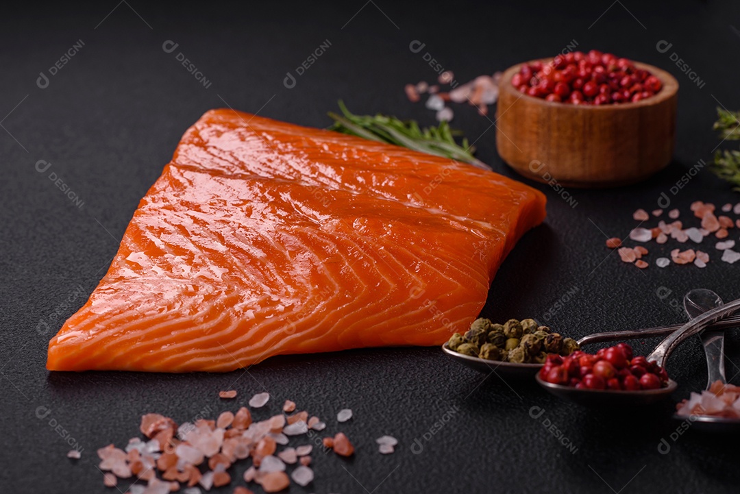 Filé de peixe salmão vermelho cru com sal, especiarias e ervas sobre um fundo escuro de concreto