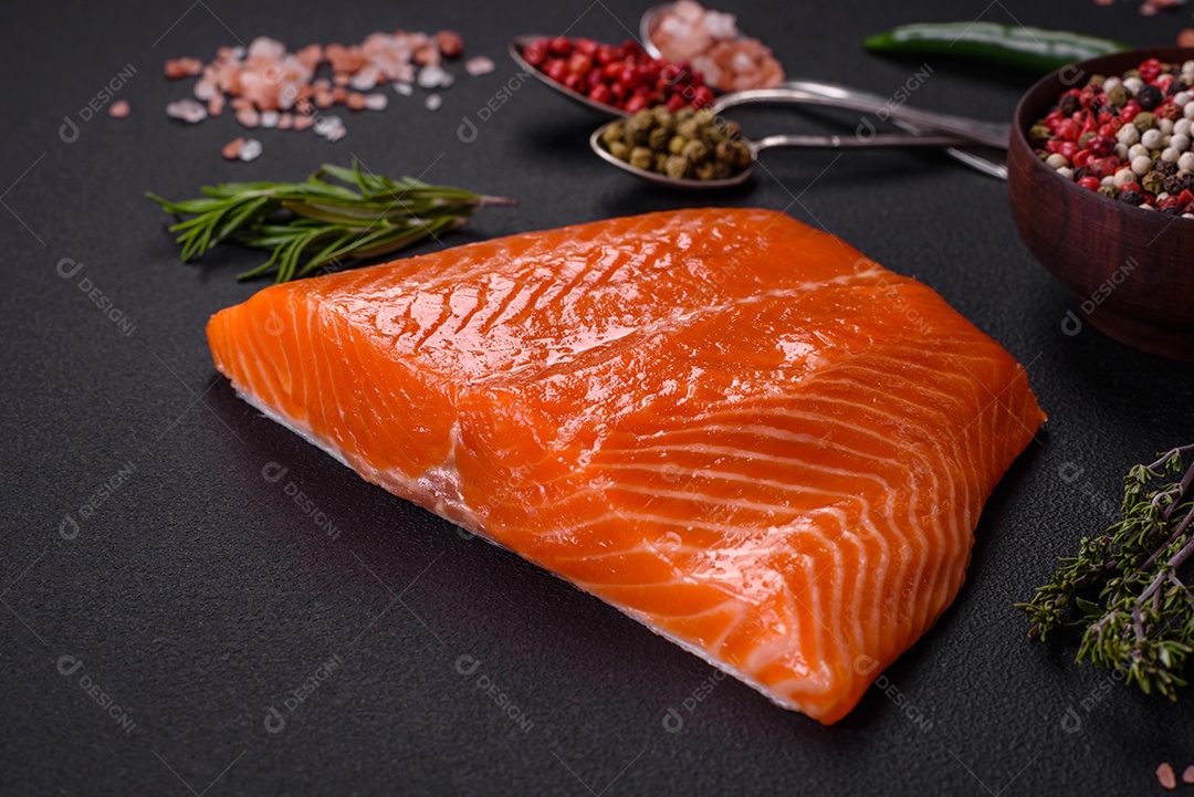 Filé de peixe salmão vermelho cru com sal, especiarias e ervas sobre um fundo escuro de concreto