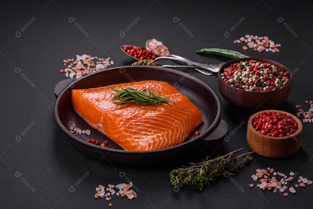 Filé de peixe salmão vermelho cru com sal, especiarias e ervas sobre um fundo escuro de concreto