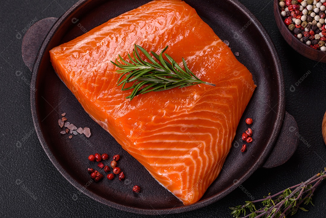 Filé de peixe salmão vermelho cru com sal, especiarias e ervas sobre um fundo escuro de concreto