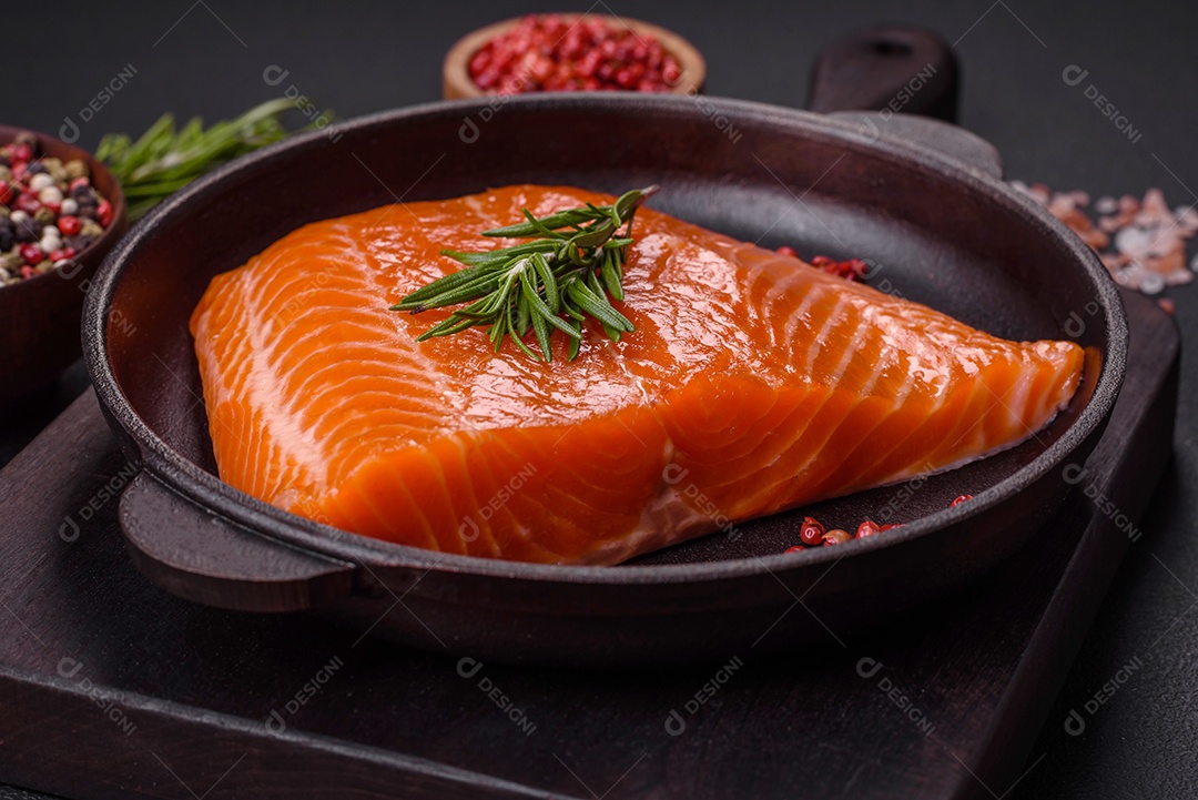 Filé de peixe salmão vermelho cru com sal, especiarias e ervas sobre um fundo escuro de concreto
