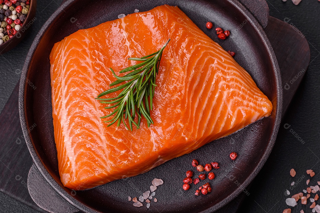 Filé de peixe salmão vermelho cru com sal, especiarias e ervas sobre um fundo escuro de concreto