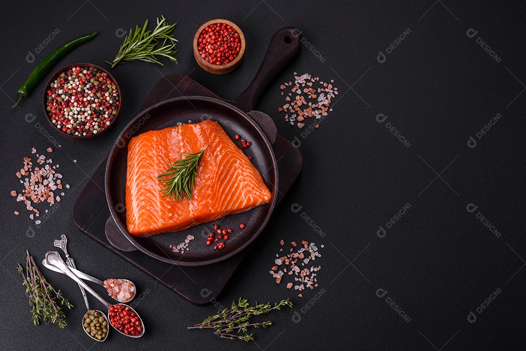Filé de peixe salmão vermelho cru com sal, especiarias e ervas sobre um fundo escuro de concreto