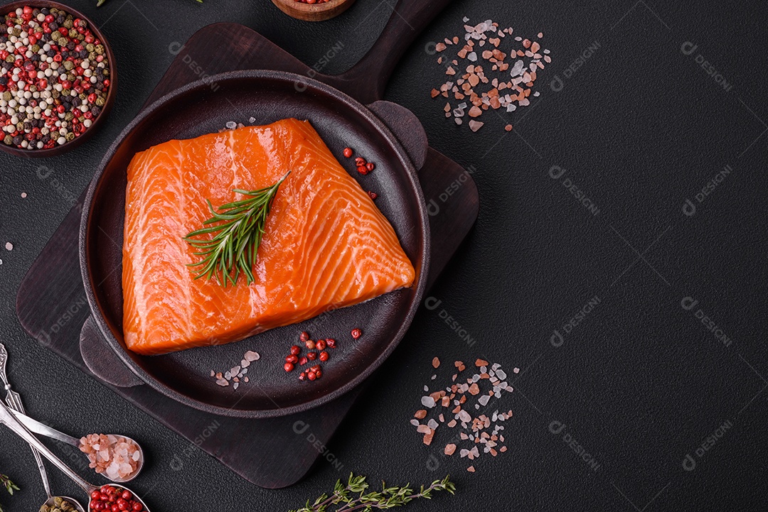 Filé de peixe salmão vermelho cru com sal, especiarias e ervas sobre um fundo escuro de concreto