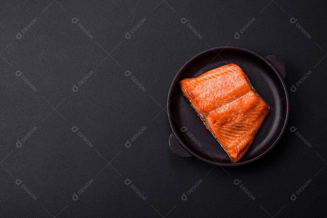 Delicioso filé de peixe vermelho salmão cozido com especiarias e ervas sobre um fundo escuro de concreto