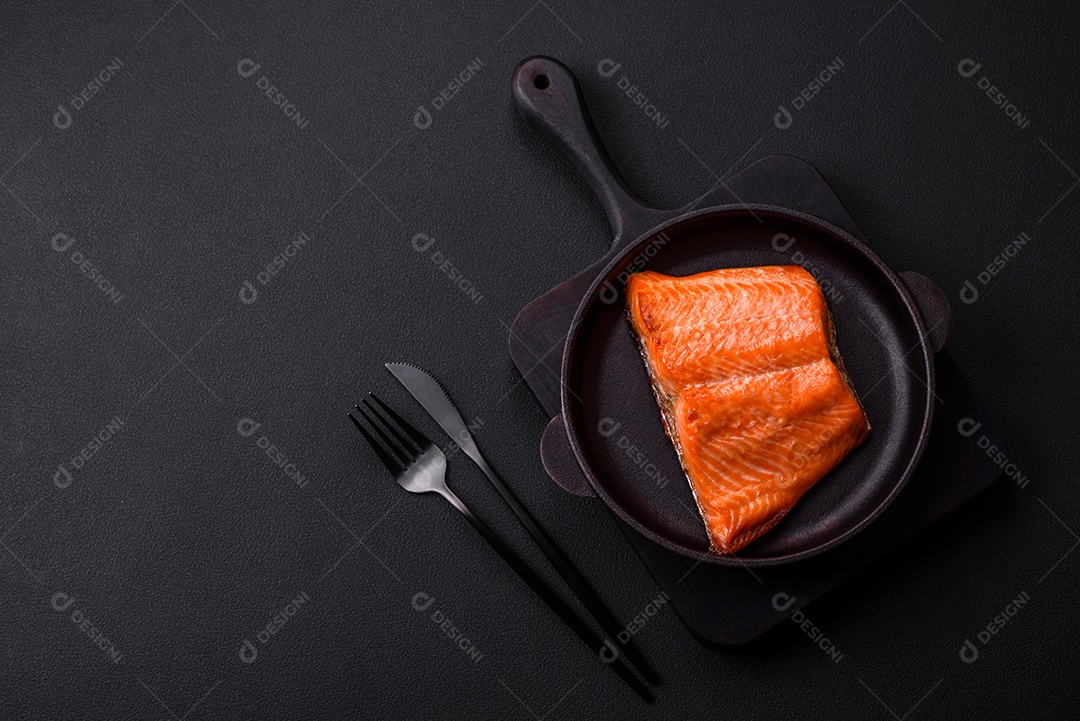 Delicioso filé de peixe vermelho salmão cozido com especiarias e ervas sobre um fundo escuro de concreto
