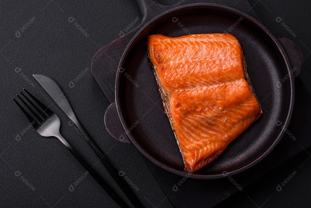 Delicioso filé de peixe vermelho salmão cozido com especiarias e ervas sobre um fundo escuro de concreto